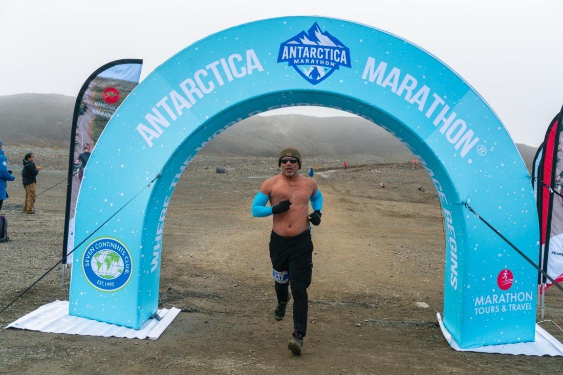 Akash running through the Antarctica Marathon finish arch — continent #5.